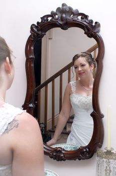 A newly married bride is admiring herself in the mirror on her wedding day.