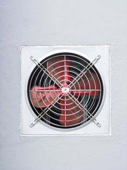 A red industrial ventilated fan on grey wall as background