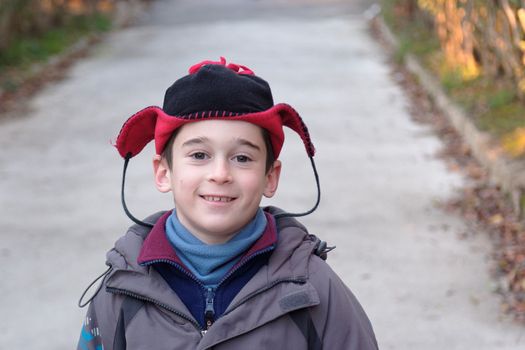 Cute little boy head in a funny hat outdoor in autumn