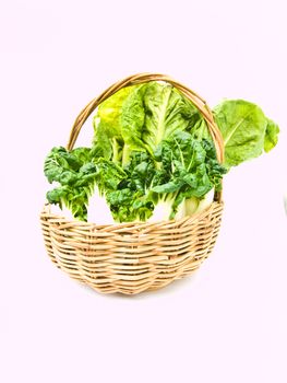 Fresh baby bok choy and cos salad in ratten basket isolated on white background