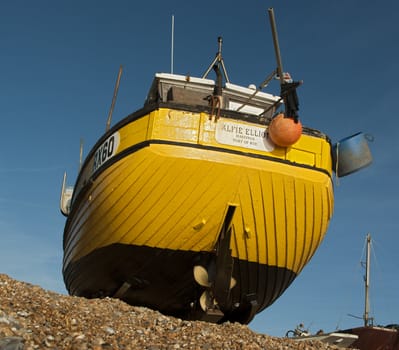 Yellow fishing boat sits on beach at Hastings England after returning from the sea