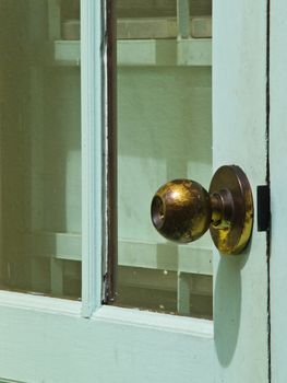 A used brooze doorknob on light blue door