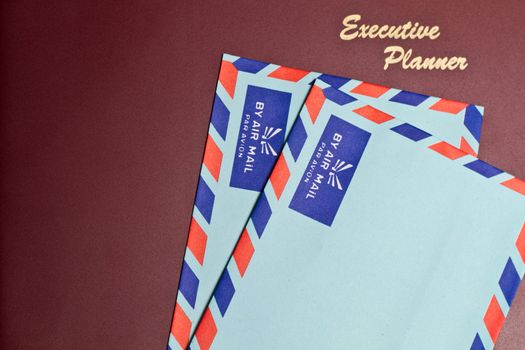 a dark red executive planner with two blue color envelopes