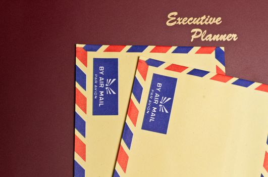 a dark red executive planner with two yellow color envelopes