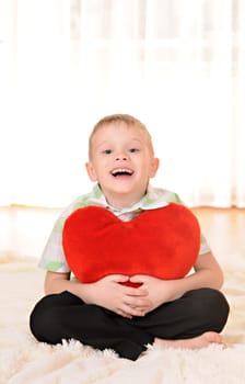 the child sit on the floor with a red plush heart