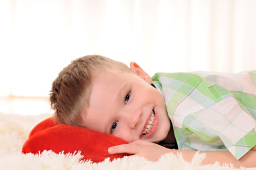 the child is lie on the floor with a red plush heart