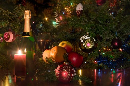 Candle, wine, and fruit on a background of a christmas fur-tree