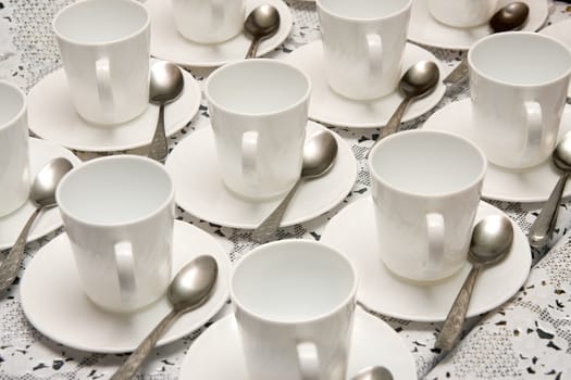 Many white cups for tea with teaspoons 