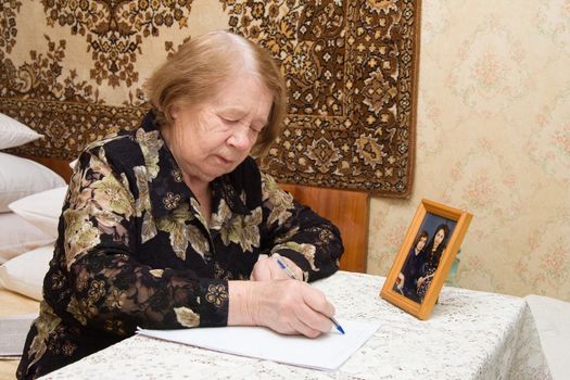 The elderly woman writes the letter to relatives