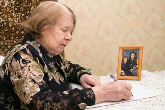 The elderly woman writes the letter to relatives