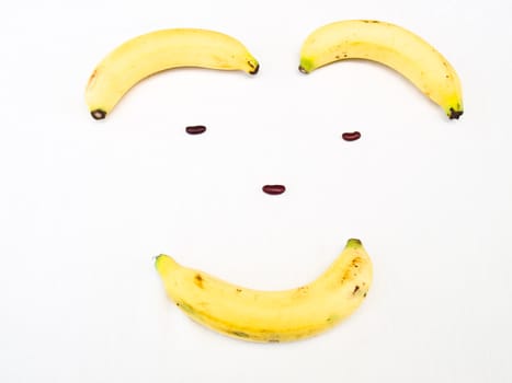 Smiling face made from banana and kidney bean Banana isolated on white