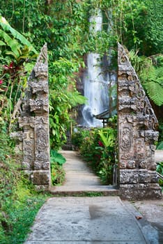 Traditional double stone gate on sacred waterfall Gingit on background