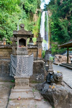 Traditional Balinese house of spirits with sacred waterfall Gingit on background