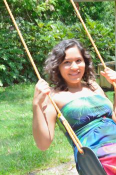Young lady swinging on a back yard rope swing