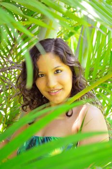 Attractive young brunette looking through the palm tree foliage