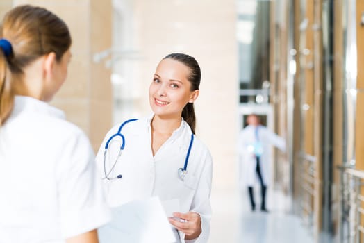 two doctors talking in the lobby of the hospital, holding the documents in the background go to other doctors