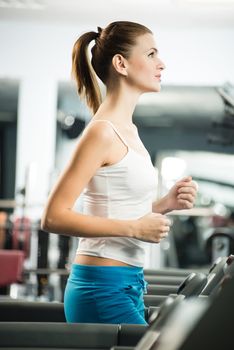 attractive young woman runs on a treadmill, is engaged in fitness sport club