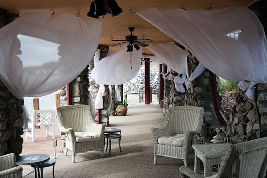 An outdoor seating patio with white sheets blowing in the wind