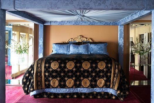 A large king bed with blue canopy and mirrors