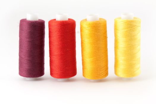 Four colored thread spools isolated on white background
