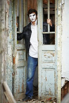 Guy mime against the old wooden door. Mime looks out of the door