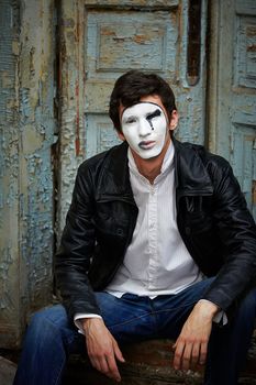 Guy mime against the old wooden door. Mime his back to the door and looks into the camera