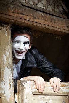 Portrait of a Man ​​mime. Grimacing near the old wooden door with peeling paint