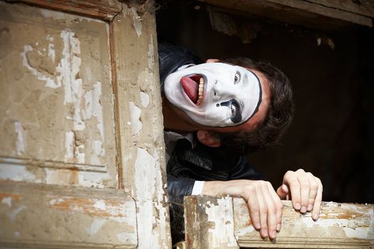 Portrait of a Man ​​mime. Grimacing near the old wooden door with peeling paint. Cocked his head