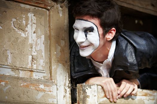 Portrait of a Man ​​mime. Grimacing near the old wooden door with peeling paint
