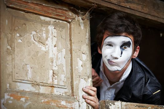 Portrait of a Man ​​mime. Grimacing near the old wooden door with peeling paint