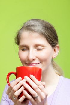 Woman savouring a mug of hot coffee smiling in bliss as she breathes in the rich aroma