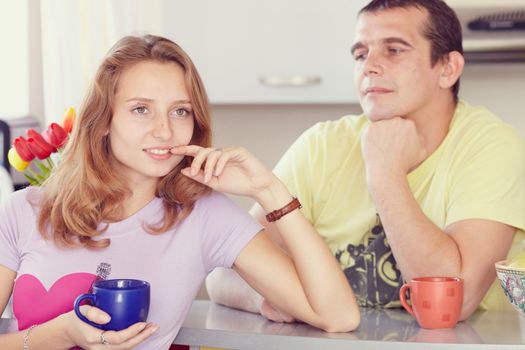 Couple in the kitchen drinking tea. Looks lovingly at his wife