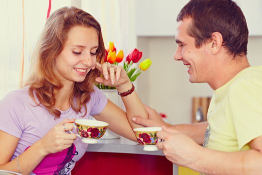 Couple in the kitchen drinking tea. Looks lovingly at his wife