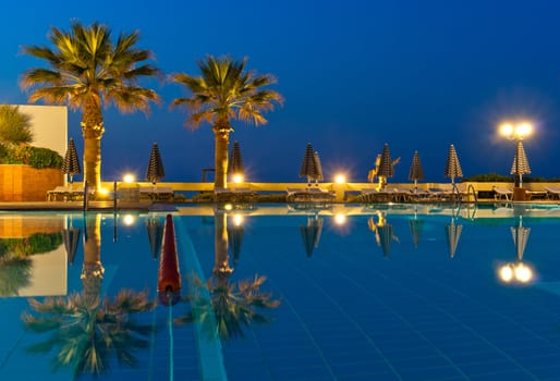 View of luxury poolside with palms on sunset