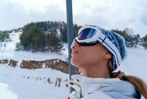 Portrait of beautiful skier in ski lift looking at sky