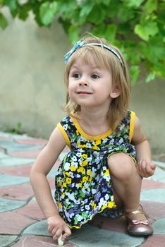 Little girl drawing images by chalk on a sidewalk