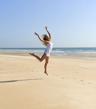 Happy beautiful woman jumping on sunny beach
