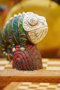 Figurine of chameleon on a chess-board. General plan