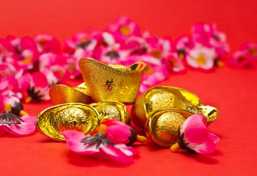 Golden Ingots with plum blosoms on red surface and background for Chinese New Year usage