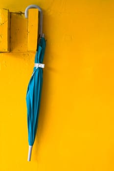 Green umbrella hanging on yellow wall painted