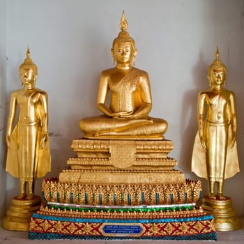 three thai golden buddha image at white wall in temple