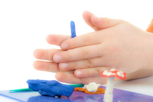 A child plays with plasticine, models figurines