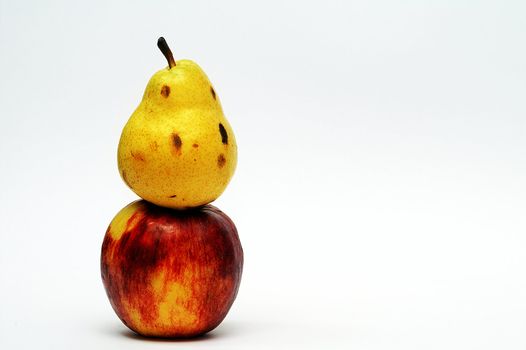 Yellow pear on top of red apple