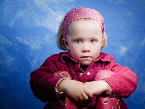 Little girl in studio in front of a blue wall