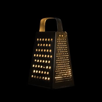 Candle in the metalic grater on a black background