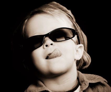 Little girl with sunglasses and a scarf sticking out her tongue