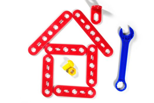 Plastic spanner and the house from the meccano (toy construction set) on a white background