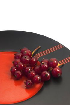 Berries of red currant on the black-red plate