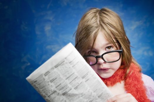 Young Girl Dressed Up in Reading Glasses Reading a Newspaper