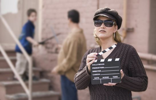 Woman holding a film slate in front of a man and boy